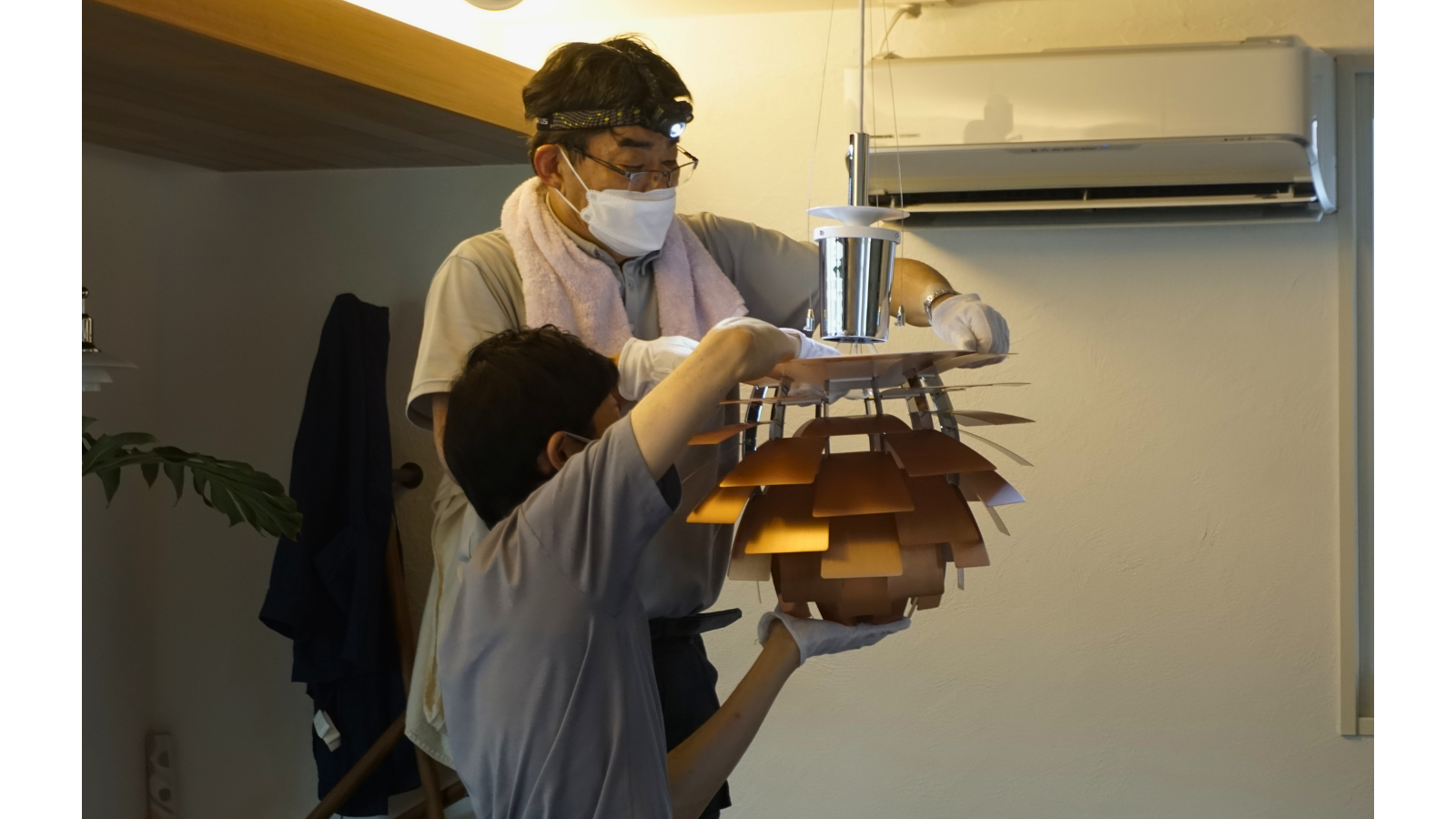 重量のあるルイスポールセン「PHアーティチョーク」を、2人の専門スタッフで慎重に天井へ吊り下げる取り付け作業