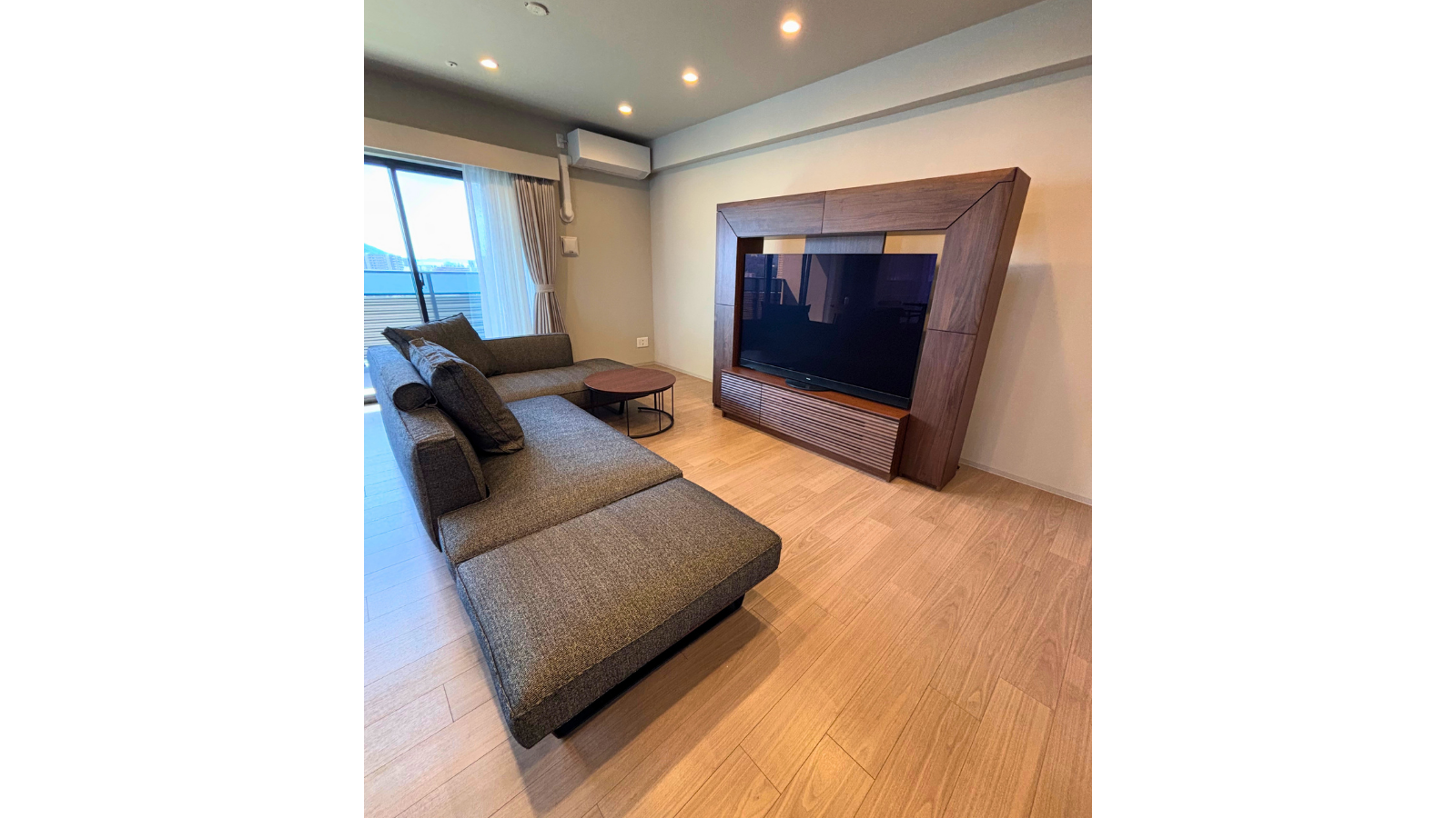 ウォールナット無垢材の大型テレビボードとグレーのソファを組み合わせたリビングのコーディネート